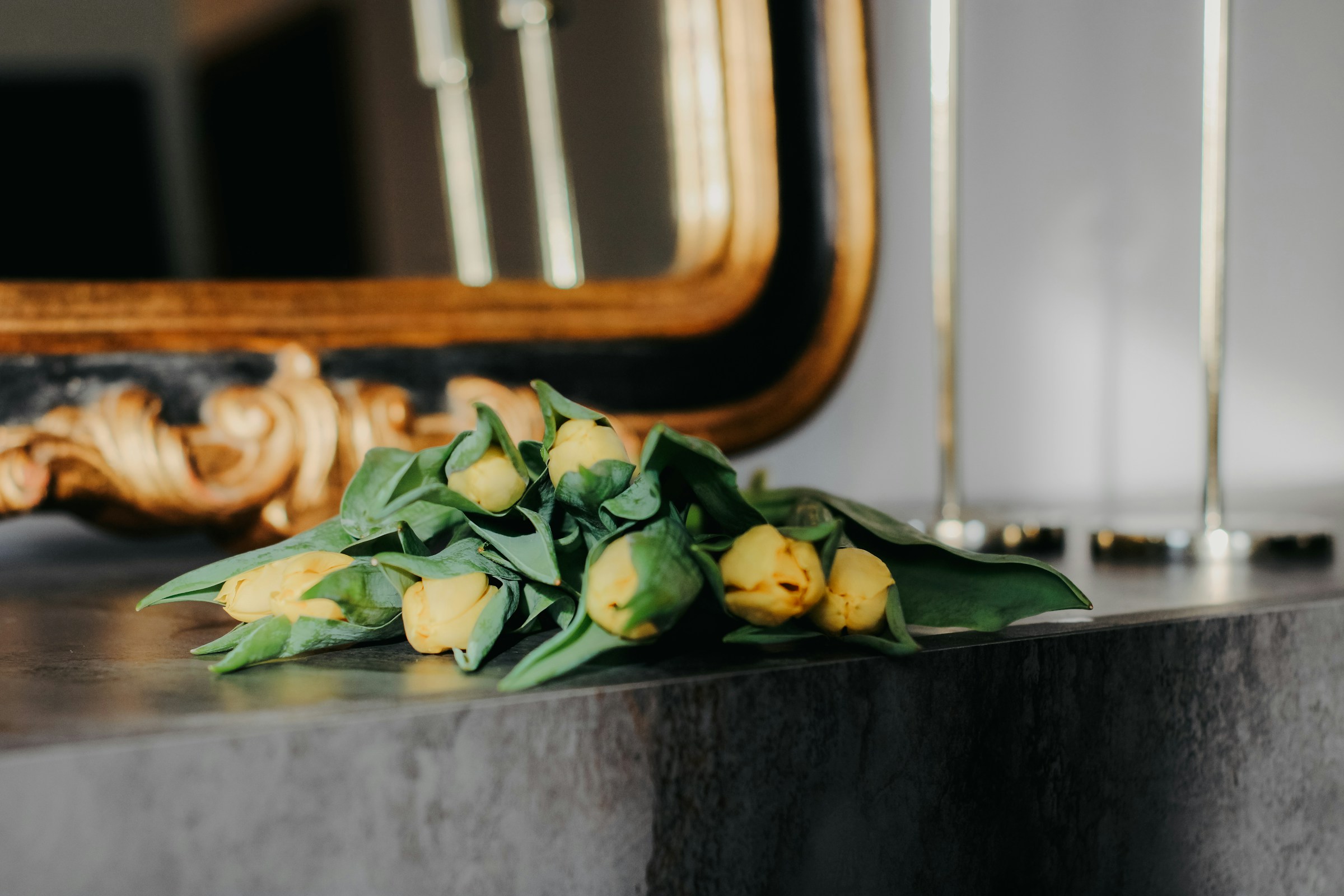 Peonies on a classic marble mantel beneath a tall gilt overmantel mirror